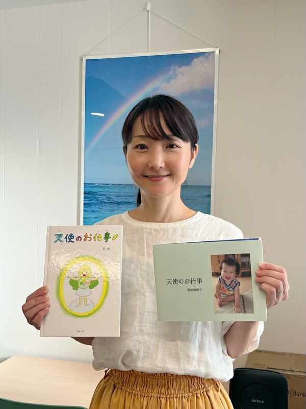 絵本を手にほほえむ講師・勝治麻由子の写真
